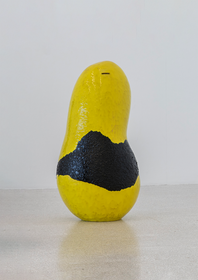 Gelb-schwarze Spardose aus Keramik mit grober Oberflächenstruktur, die auf dem Boden steht